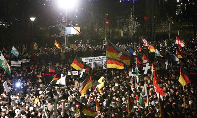 Supporters of anti-immigration movement Patriotic Europeans Against the Islamisation of the West (PEGIDA) hold flags during a demonstration in Dresden