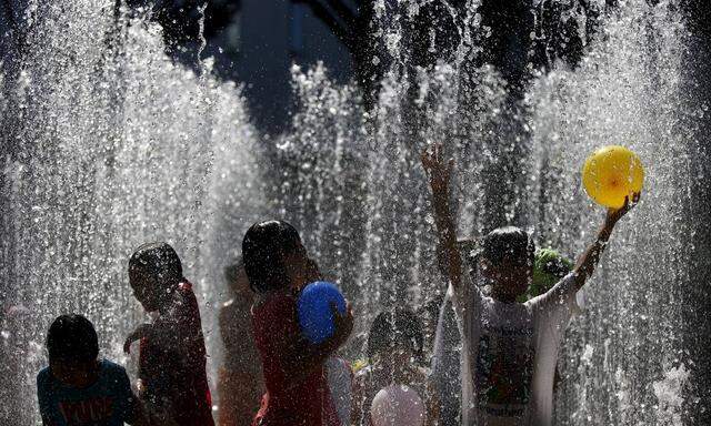 Children cool down in a water fountain at a park in Tokyo