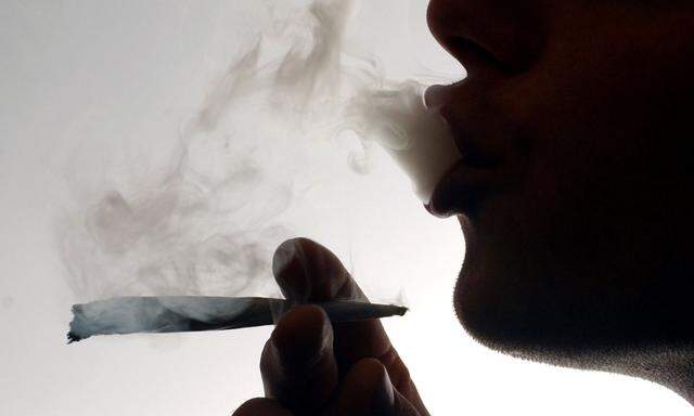 FILE PHOTO: An unidentified man smokes a cannabis cigarette at a house in London