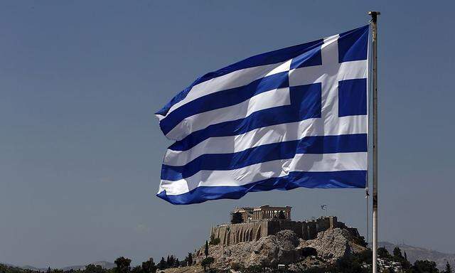 A Greek flag flutters in front of the Acropolis hill in Athens