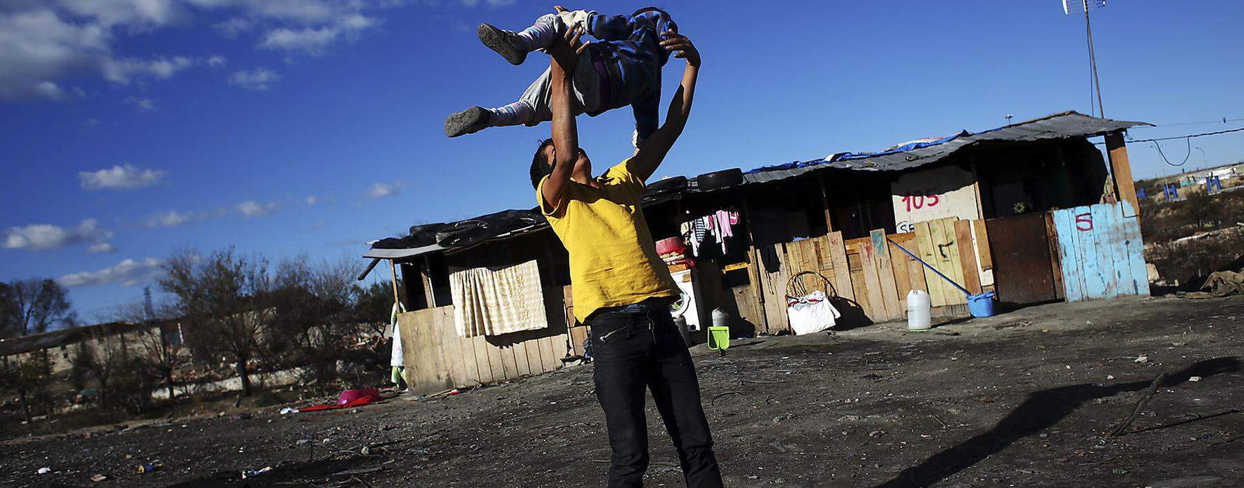 Leon throws his brother Samuel in the air as they play outside their home in the shanty town settlement of El Gallinero, in the outskirts of Madrid
