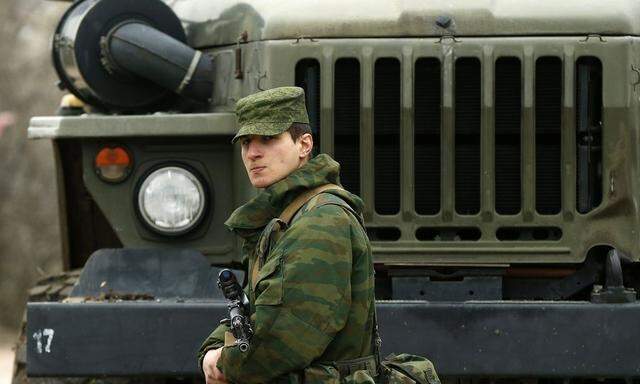 A uniformed man, believed to be Russian serviceman, stands guard near a Ukrainian military base outside the city of Sevastopol
