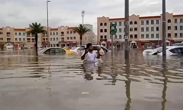 Ein Mann watet durch Wassermassen in Dubai.