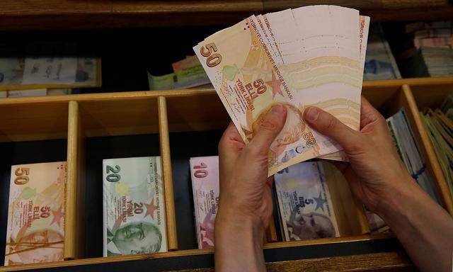 A money changer counts Turkish lira banknotes at a currency exchange office in Istanbul