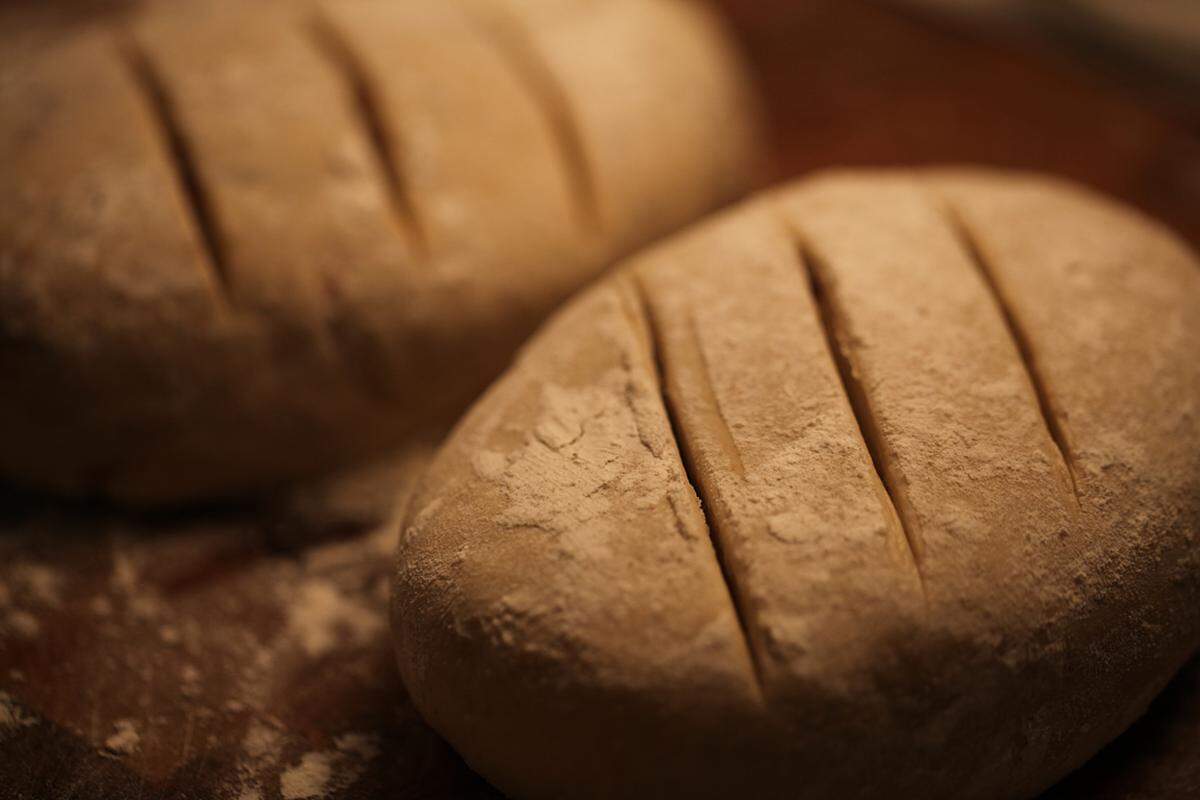 Nachdem ein paar Kerben (ca. 5 cm) in die Laibe geschnitten wurden, macht das Brot alleine im Backrohr weiter. Ein Tipp: die Laibe werden aufgehen, daher ist es besser, wenn man sie ziemlich flach drückt. 