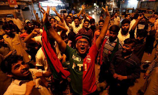 Supporters of Pakistan Tehreek-e-Insaf political party celebrate along the road during the general election in Karachi