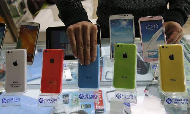 A clerk arranges Apple's iPhone 5C phones bearing the logo of  China Mobile at a mobile phone shop in Beijing