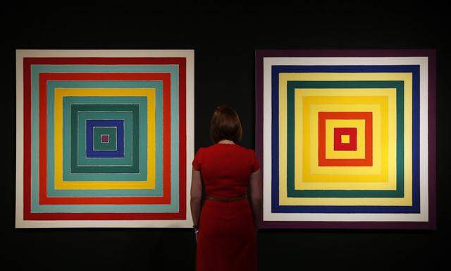 Christie´s assistants pose for photographers with Frank Stella´s ´6. Scramble: Ascending `Yellow Values / Descending Spectrum´ and  ´D. Scramble: Ascending `Green Values / Ascending Spectrum´ at Christie´s auction house in London