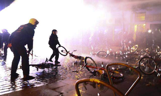 Riot police officer pulls a bicycle that protesters used as a barricade during demonstrations at the G20 summit in Hamburg