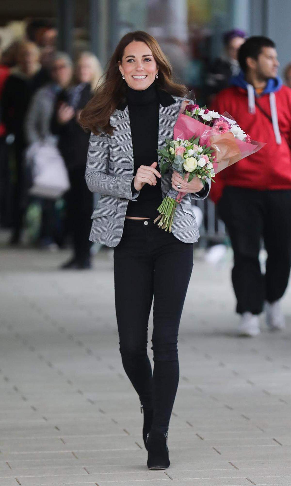 Bei einer Stippvisite in Essex durfte es auch etwas legerer zugehen. Ganz in Schwarz gekleidet, bis auf den grauen Blazer von Smythe, nahm die Herzogin Blumen entgegen - inklusive einem kleinen Bauchblitzer: Da scheint doch tatsächlich der Rollkragenpullover aus dem Hosenbund ihrer Röhrenjeans gerutscht zu sein.