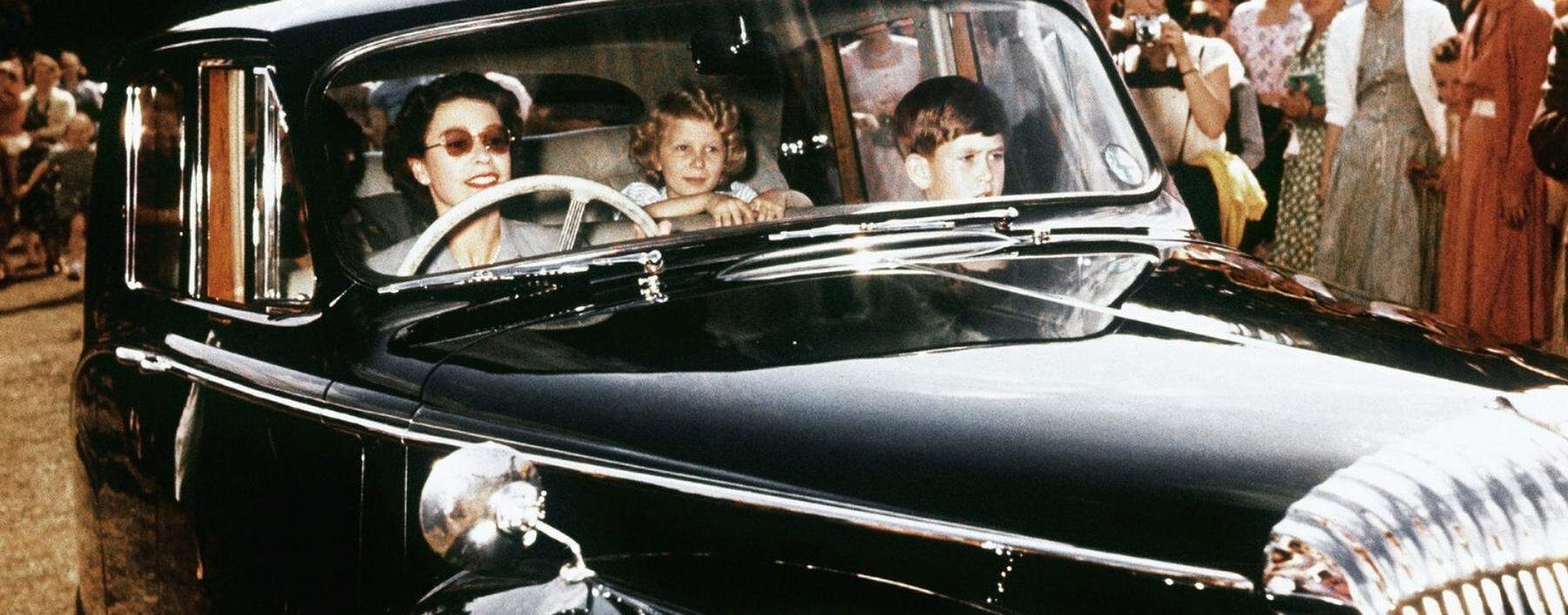 Vor Einführung von Gurtpflicht und Kindersitz: Königin Elisabeth am Steuer eines Daimler, mit Anne und Charles, 1957. 