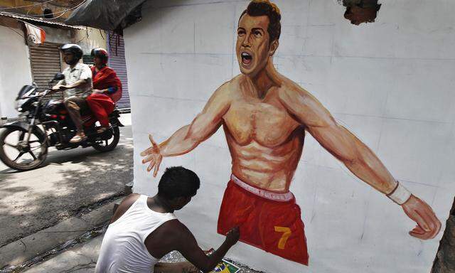 An artisan paints the wall of a house with a picture of Portugal´s national soccer player Cristiano Ronaldo, in Kolkata
