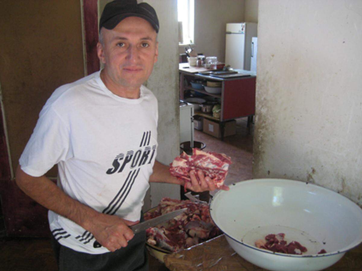 An der inoffiziellen Autobahnraststätte wird Fleisch geschnitten. Dieser Mann erzählt, er komme aus Tadschikistan, aber hier sei es besser als dort, wo er herkomme.