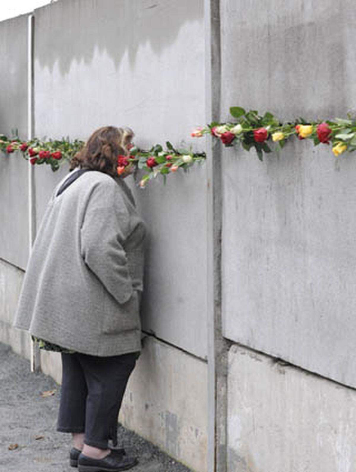 In der Berliner Bernauer Straße, wo eines der wenigen erhaltenen Teilstücke der Mauer steht, gedenken Menschen an die Todesopfer der Teilung.