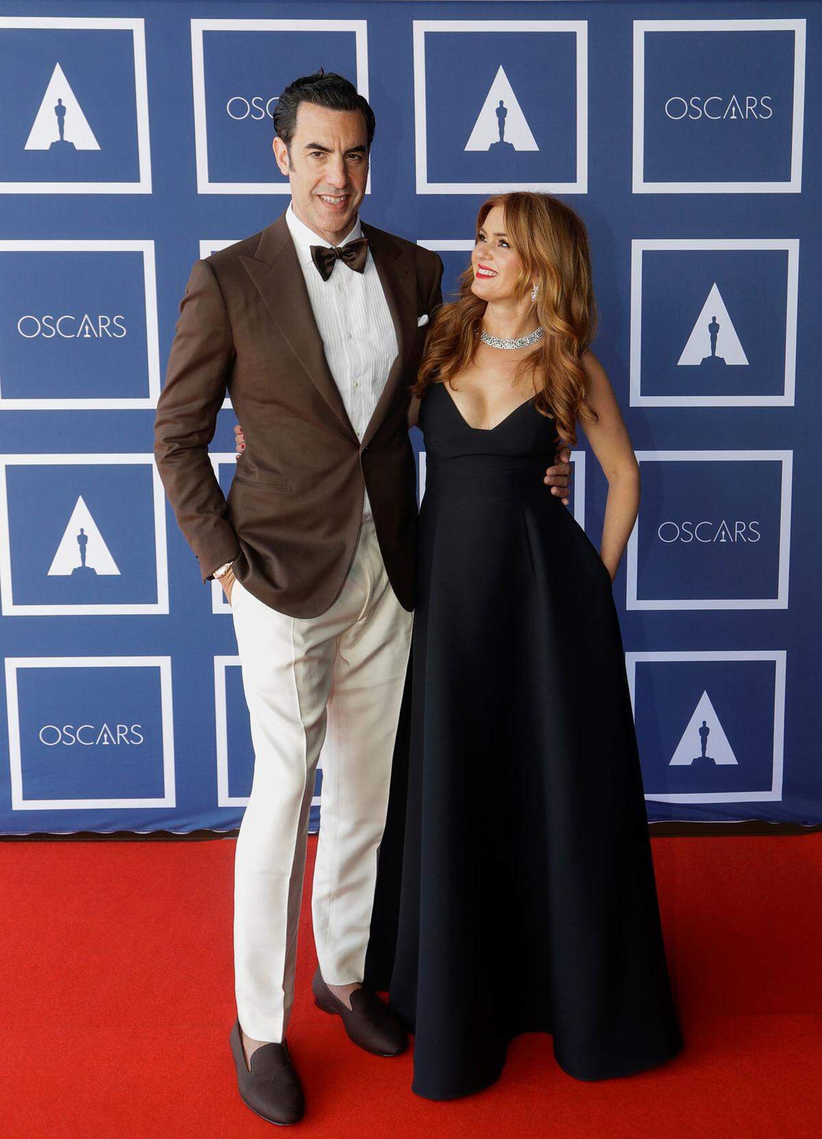 Isla Fisher neben ihrem Mann Sacha Baron Cohen. Sie in einer Robe von Dior, er in einem handgefertigten Mokka-Anzug von Ralph Lauren Purple Label.