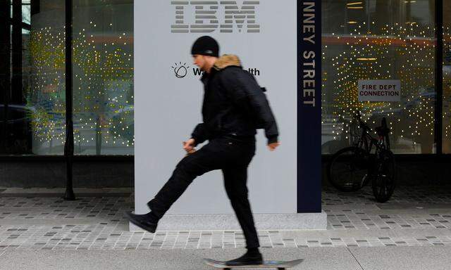 A skateboarder passes the sign for an IBM office in Cambridge