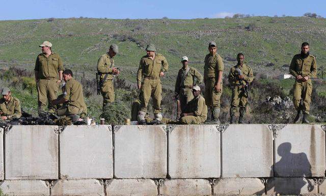 Israeli soldiers stand on concrete blocks near the border with Lebanon