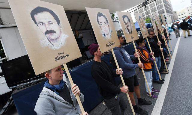 Demonstranten halten bei einer Kundgebung vor dem Oberlandesgericht Schilder mit Abbildungen der NSU-Opfer. 