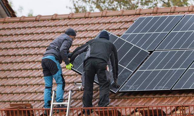 Symbolbild: Techniker montieren eine Photovoltaikanlage auf dem Dach eines Wohnhauses