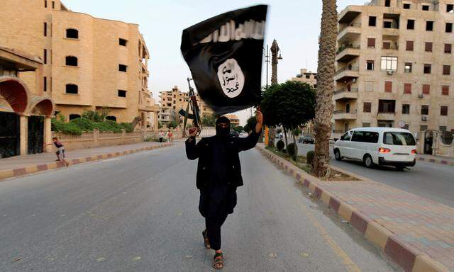 Symbolbild: Kämpfer hält die IS-Flagge in der Stadt Raqqa