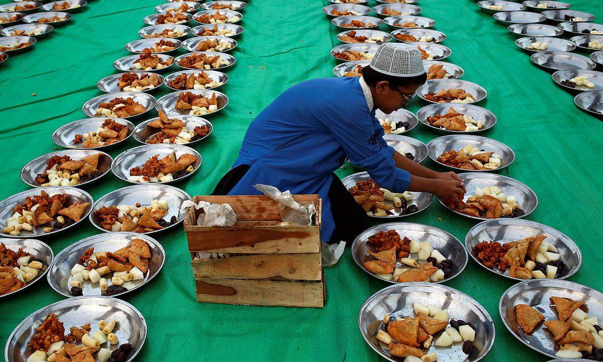 Wenn sich Muslime bei Sonnenuntergang versammeln, um gemeinsam das Fasten zu brechen, wird das Iftar genannt. Viele essen mit der Familie, aber auch Moscheen laden zum gemeinsamen Iftaressen ein. Ein junger Mann bereitet Essensportionen vor für das Fastenbrechen vor der Moschee von Karatschi, Pakistan