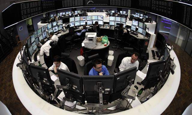 Traders are pictured at their desks in front of the DAX board at the Frankfurt stock exchange