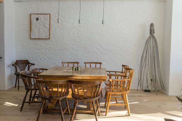 Traditionell trifft Minimalistisch: Esstisch und Sessel aus Holz, Wanddesign in Weiß und Metall.