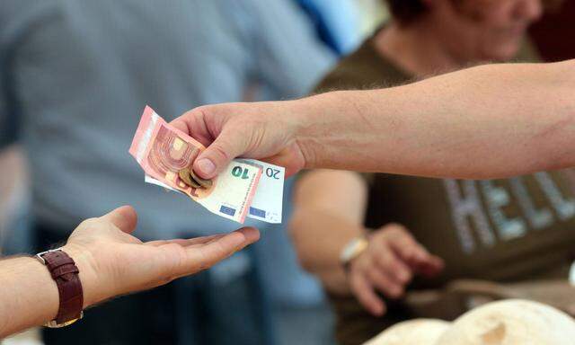 Frau reicht einer Marktverk�uferin einen Euro Geldschein zum Bezahlen ihrer gekaufter Ware Viktuali
