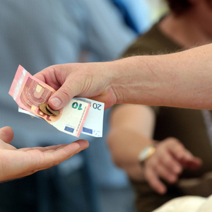 Frau reicht einer Marktverk�uferin einen Euro Geldschein zum Bezahlen ihrer gekaufter Ware Viktuali