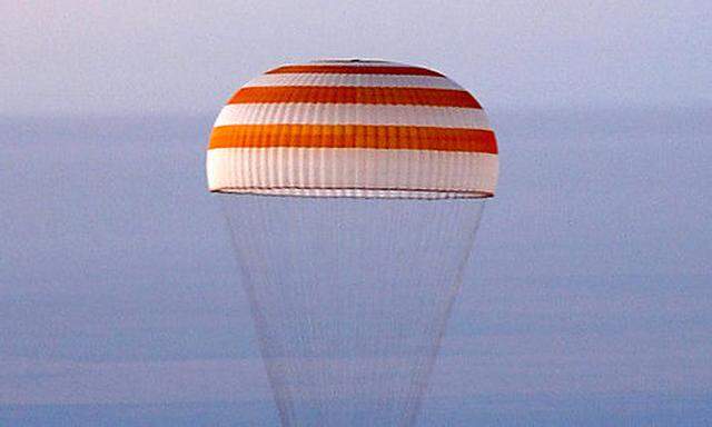 The Soyuz space capsule under a parachute flies before the landing in northern Kazakstan Friday, Sept