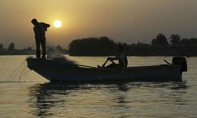 A fisherman casts a net as he fishes in Euphrates river in Falluja