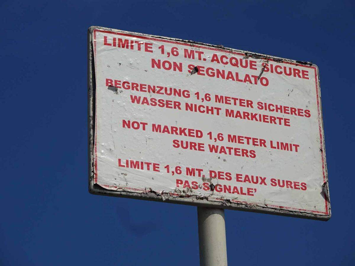 Das rätselhafteste Schild des Lido steckt im seichten Gewässer des „Blue Moon“. Auf jeder einzelnen Sprache wird der Sachverhalt irgendwie verschleiert, aber wenn man alle zusammen liest, versteht man die Botschaft durchaus.