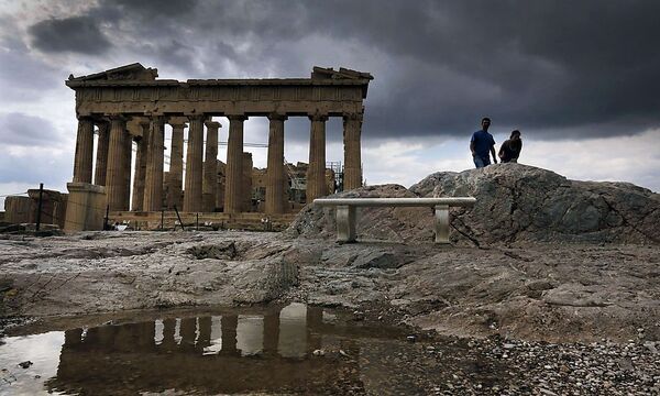 Tourists visit the Athens Acropolis during a rainy day