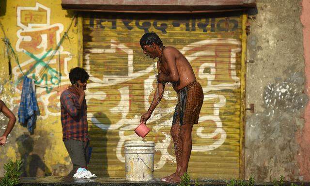 Desinfizierung in einem Armenviertel. Im Slum Dharavi in der indischen Millionenmetropole Mumbai verrichtet ein Bewohner Körperpflege auf der Straße.