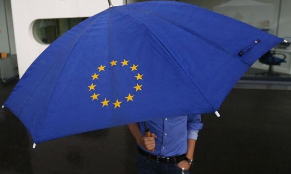 A person with an umbrella featuring the symbol of the European Union walks towards the interim facility of Germany's high constitutional court  in Karlsruhe