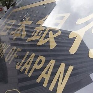 A man walks past a signboard of the Bank of Japan headquarters in Tokyo