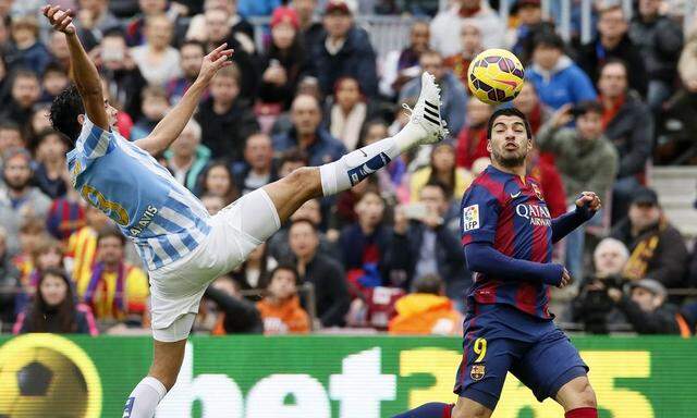 Barcelona's Luis Suarez fights for the ball against Malaga's Weligton during their Spanish First division soccer match at Camp Nou stadium in Barcelona