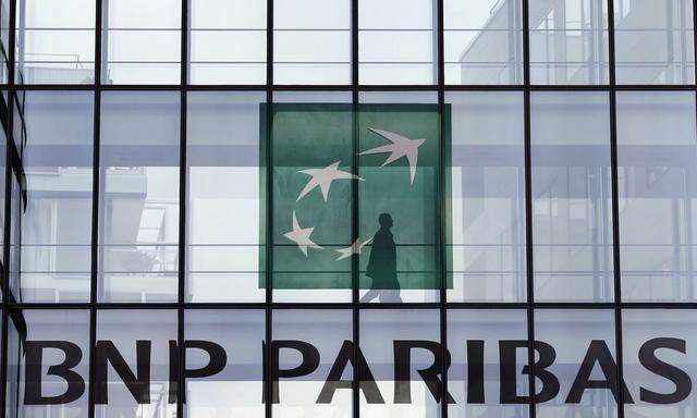 An employee walks behind the logo of BNP Paribas in a company's building in Issy-les-Moulineaux, near Paris