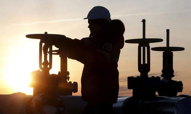FILE PHOTO: Worker checks valve of oil pipe at Lukoil company owned Imilorskoye oil field outside West Siberian city of Kogalym