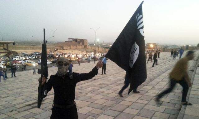 File photo of a fighter of the ISIL holding a flag and a weapon on a street in Mosul