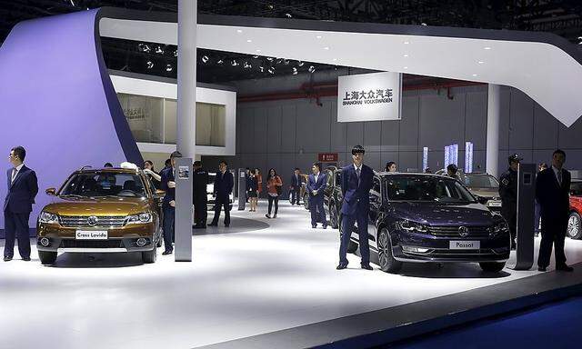 Staff personnel stand next to Volkswagen cars during 16th Shanghai International Automobile Industry Exhibition in Shanghai