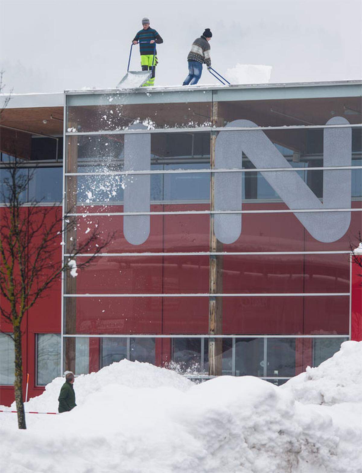 Arbeiter schaufeln das Dach eines Einkaufsmarktes in Nussdorf (Kärnten) ab.