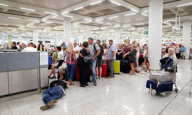 Passengers are seen at Thomas Cook check-in points at Mallorca Airport after the world's oldest travel firm collapsed, in Palma de Mallorca