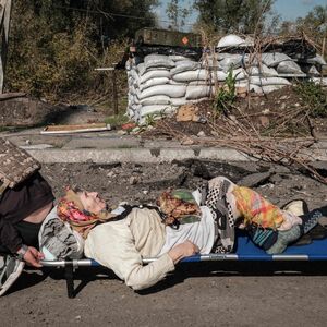 Nach dem Abzug der russischen Truppen versorgen ukrainische Freiwillige die Zivilisten in den befreiten Gebieten. Auf einer Trage wird eine 86-Jährige über die Brücke beim Fluss Oskil gebracht.