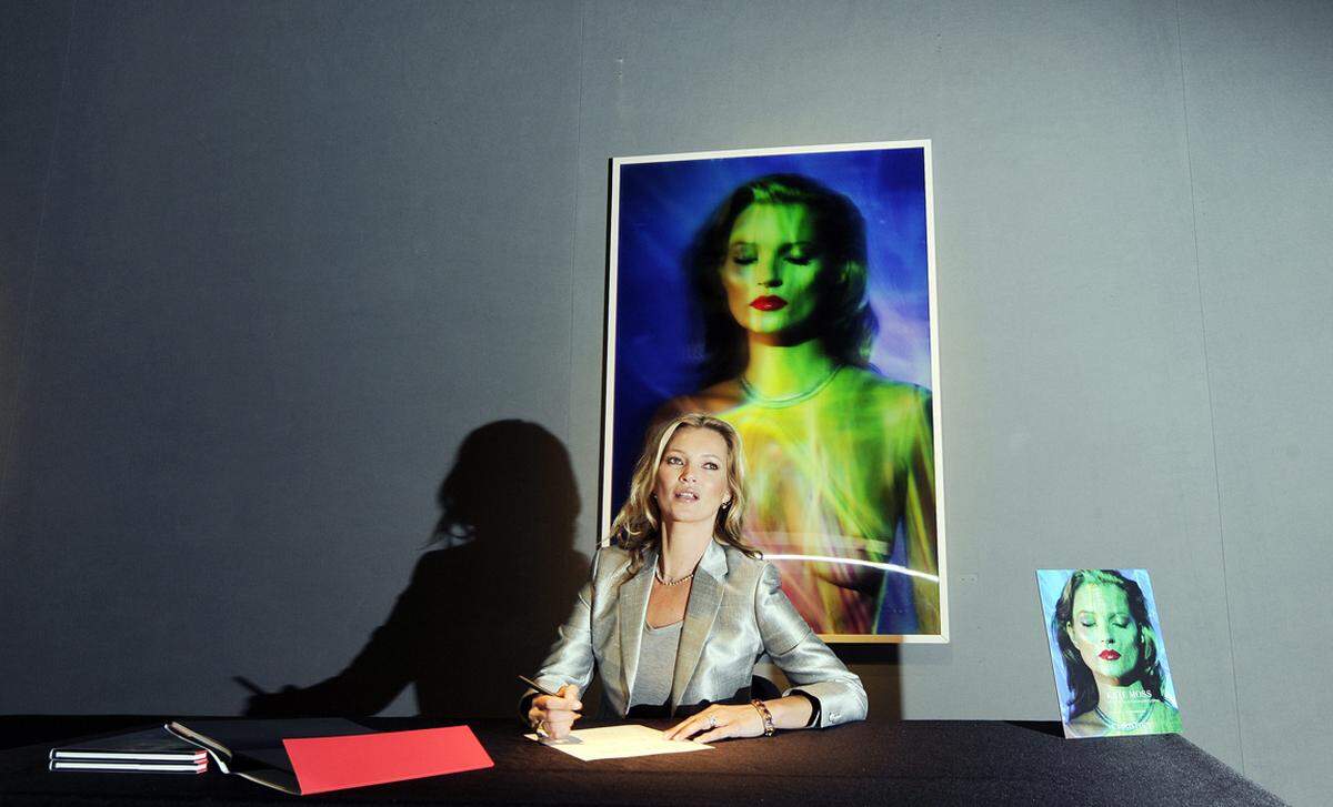 Im Zuge des Fototermins signierte das Supermodel auch einige Ausstellungskataloge. Das Bild im Hintergrund "She's Light (Laser 3)" von Chris Levine soll 414.000 Euro Wert sein.