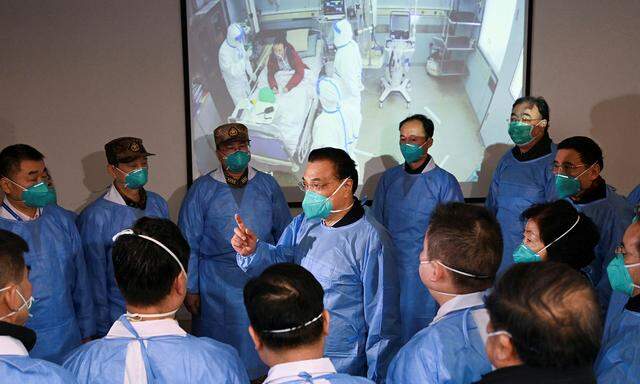 Chinas Premierminister Li Keqiang (Mitte) spricht in einem Krankenhaus in Wuhan zu Personal und Sicherheitskräften. 