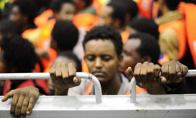 Migrants from Sub-Saharian areas stand on a landing craft of Italy's Navy ship San Giorgio after being rescued in open international water in the Mediterranean Sea between the Italian and the Libyan coasts