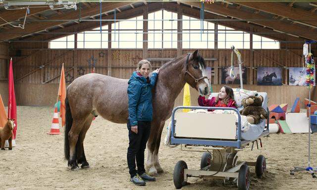 Therapeutin Roswitha Zink mit der neunjährigen Fini, die mit Therapiepferd Kurumi im Krankenbett übt.