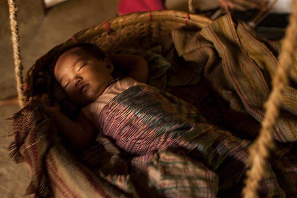 Eine Jumma-Mutter in den Chittagong Hill Tracts, der bergigen Region im Südwesten Bangladeschs, legt ihr Neugeborenes in ein traditionelles Bett, ein dhulon, und singt es in den Schlaf mit den als olee daagaanaa bekannten Kinderliedern. Heute sind die Jumma und ihre Kinder eine Minderheit gegenüber zugezogenen Siedlern und werden vom Militär gewaltsam unterdrückt.