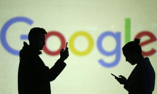 Silhouettes of mobile users are seen next to a screen projection of Google logo in this picture illustration
